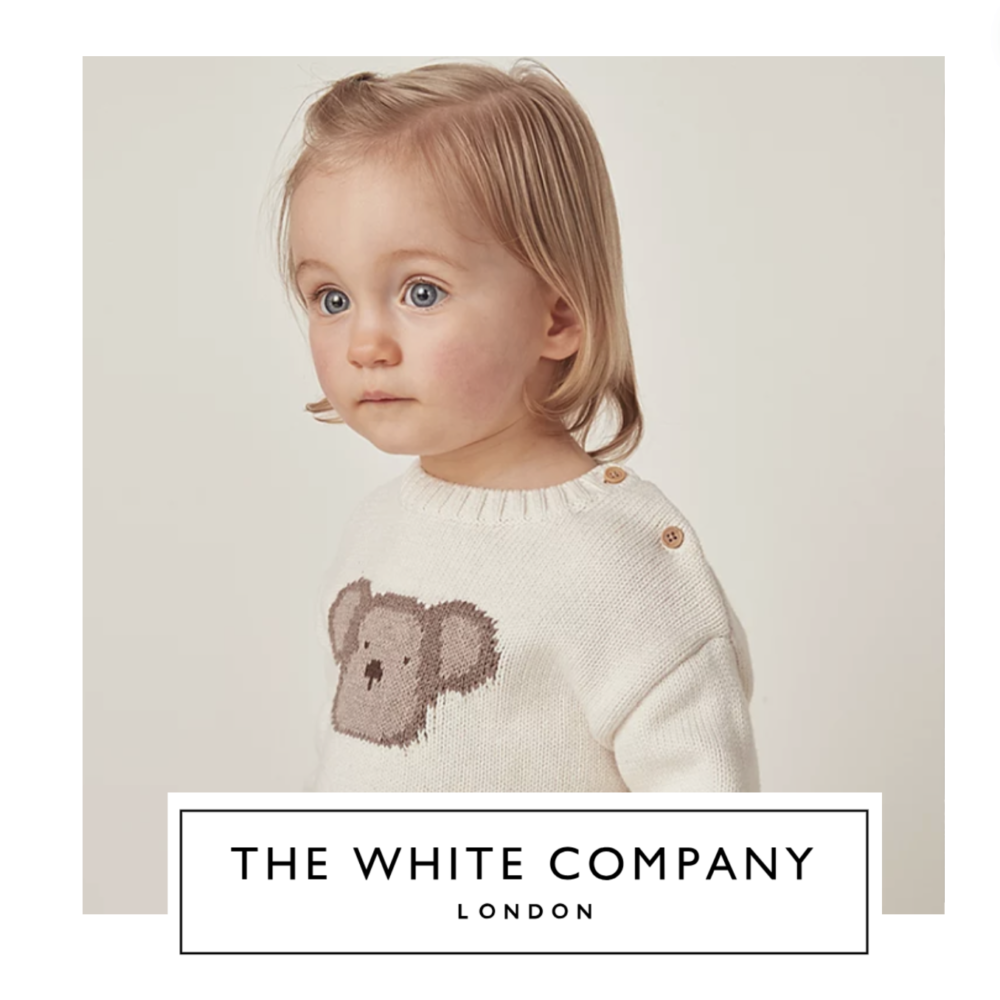 CHILD MODELLING A CREAM JUMPER WITH TEDDY BEAR BY THE WHITE COMPANY